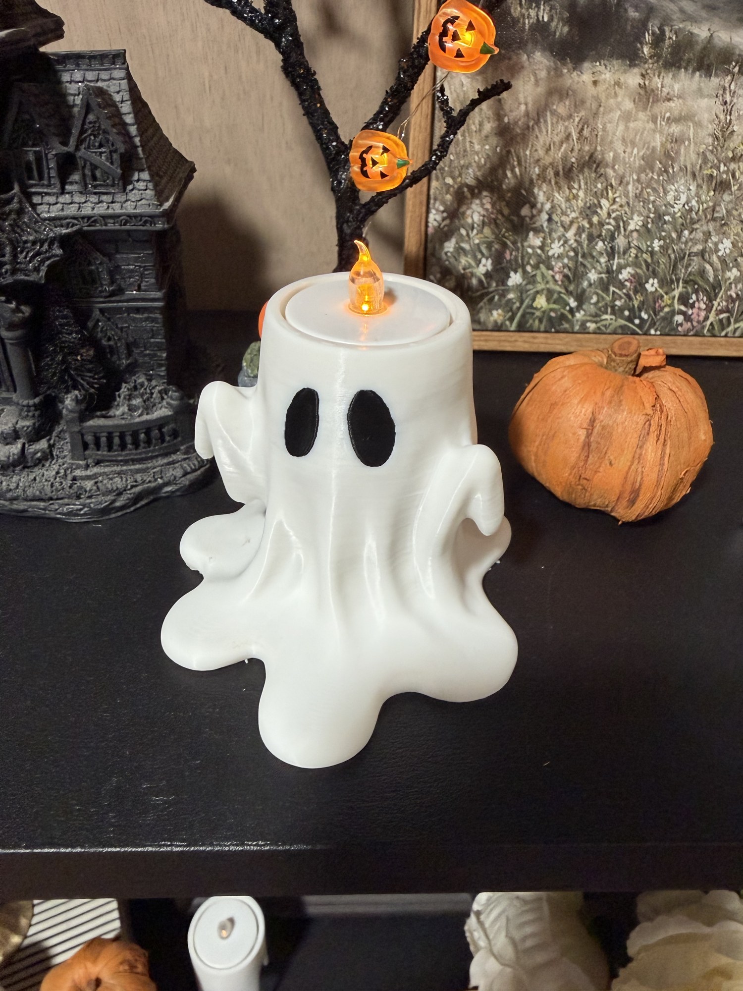 White Drippy Ghost tea light holder shown at an angle with Halloween decor